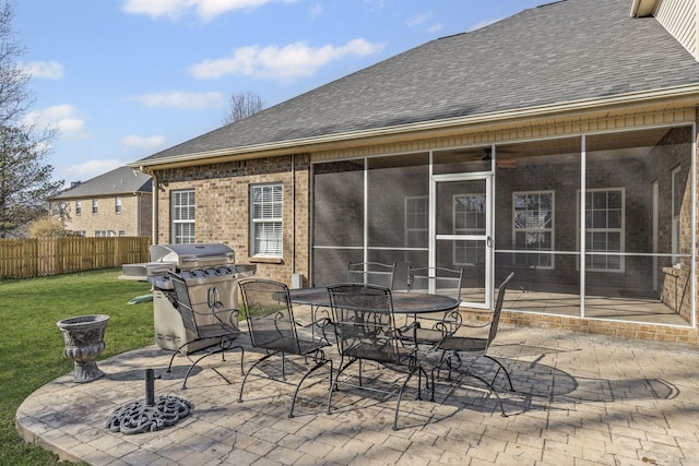 view of patio featuring outdoor dining space, fence, a sunroom, and grilling area