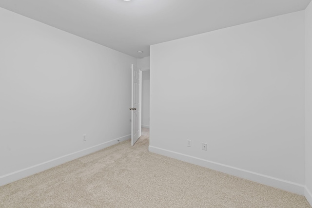 unfurnished room featuring baseboards and light colored carpet