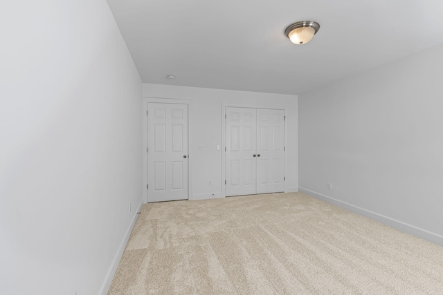 unfurnished bedroom featuring baseboards, light carpet, and a closet