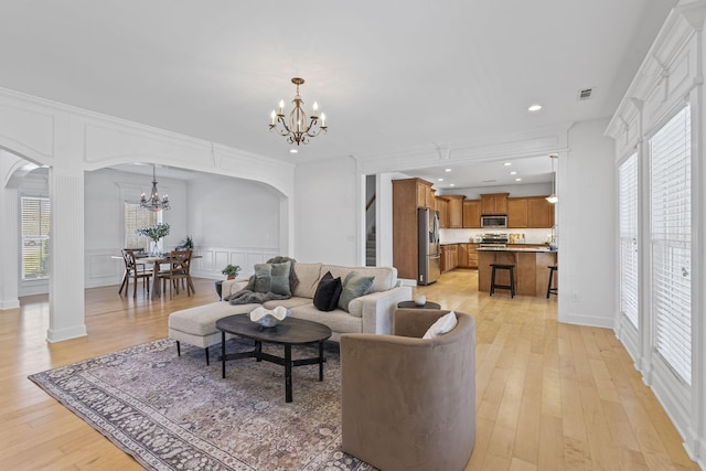 living room with a decorative wall, visible vents, arched walkways, and a chandelier