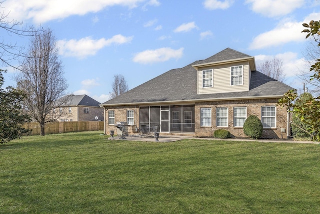 rear view of property with fence, a yard, a sunroom, brick siding, and a patio area