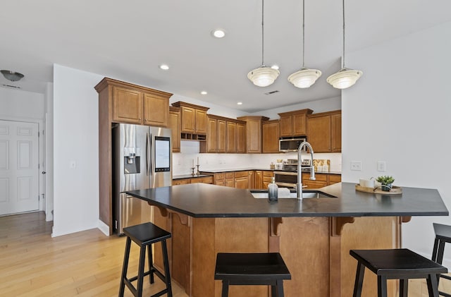 kitchen with a sink, dark countertops, brown cabinets, and stainless steel appliances