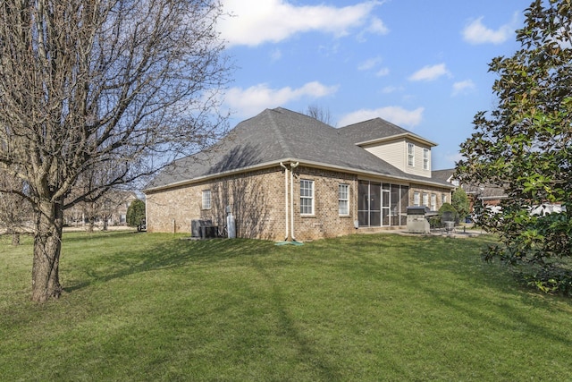 rear view of property with central air condition unit, a lawn, brick siding, and a shingled roof