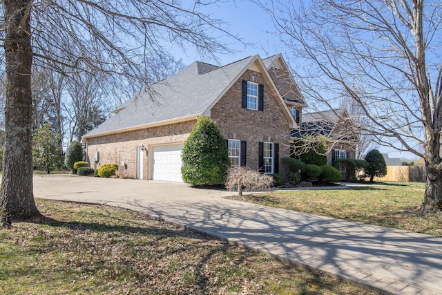 view of side of home with a yard, a shingled roof, concrete driveway, a garage, and brick siding