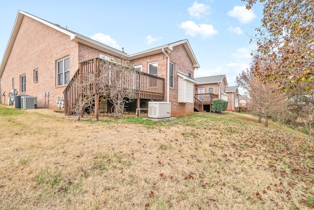 back of house featuring a wooden deck, central air condition unit, brick siding, and a yard