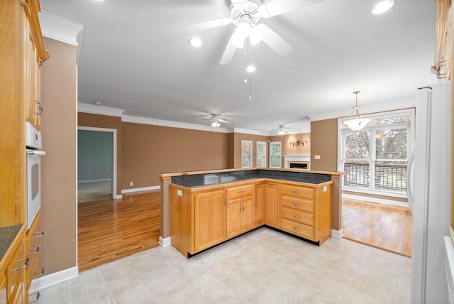 kitchen featuring dark countertops, a healthy amount of sunlight, ornamental molding, white appliances, and a ceiling fan