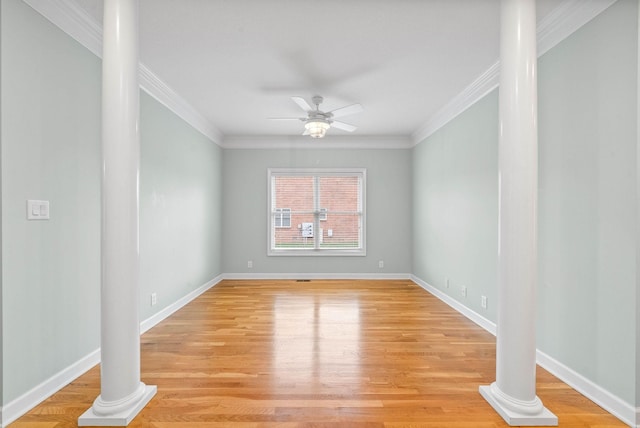 unfurnished room featuring a ceiling fan, crown molding, light wood finished floors, decorative columns, and baseboards