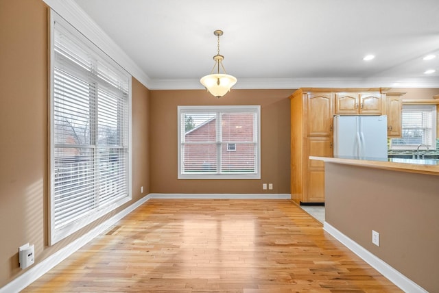 unfurnished dining area featuring visible vents, baseboards, a sink, ornamental molding, and light wood-type flooring