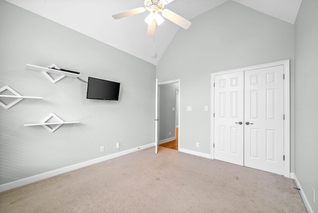 unfurnished bedroom featuring ceiling fan, baseboards, carpet floors, a closet, and high vaulted ceiling