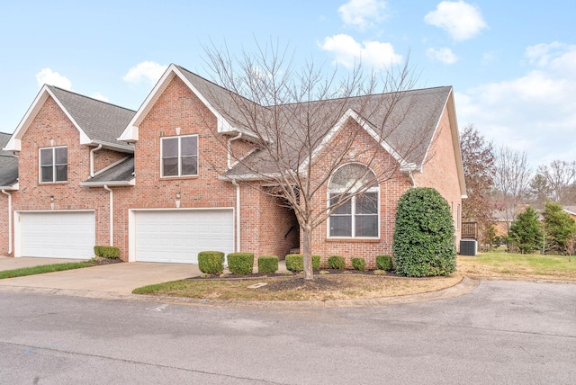 traditional-style house with central AC unit, brick siding, a garage, and driveway