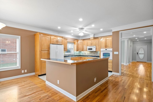 kitchen with a center island, ceiling fan, decorative backsplash, light wood-style floors, and white appliances