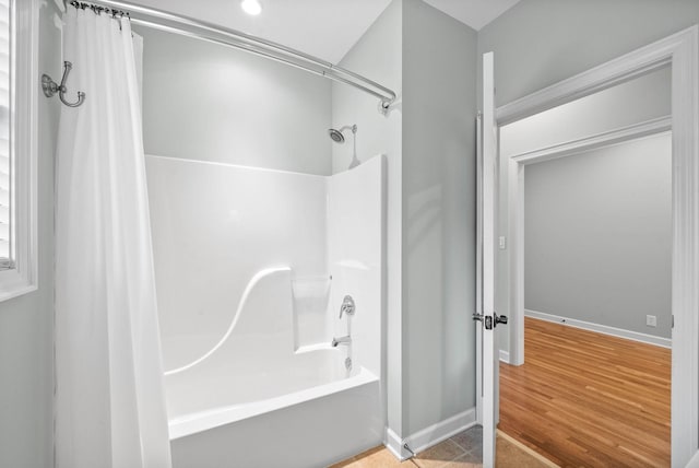 full bathroom featuring shower / bath combo with shower curtain, baseboards, and wood finished floors