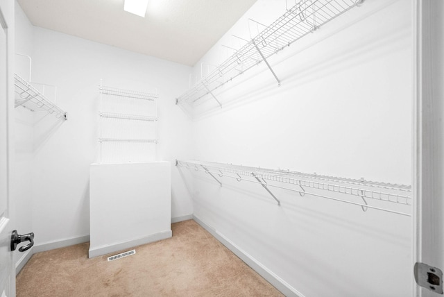 walk in closet featuring visible vents and light carpet