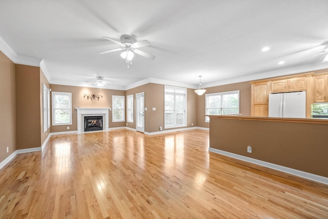 unfurnished living room featuring plenty of natural light, light wood-style floors, and ornamental molding