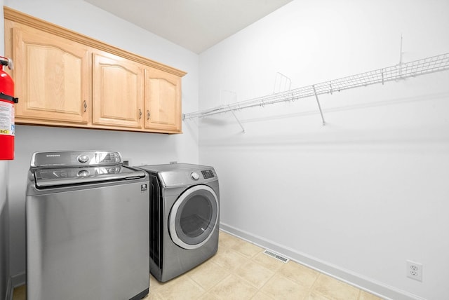 washroom with light floors, visible vents, baseboards, cabinet space, and independent washer and dryer