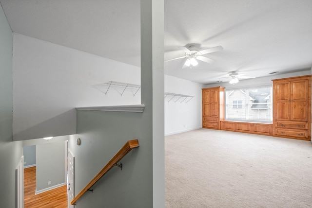 unfurnished living room with light colored carpet, baseboards, and ceiling fan