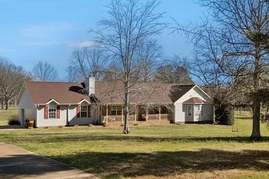 single story home featuring a front lawn, a garage, and driveway