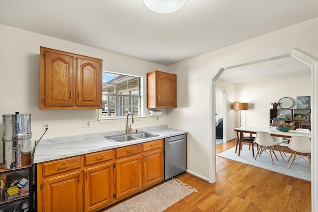 kitchen featuring brown cabinetry, a sink, light countertops, dishwasher, and light wood-type flooring