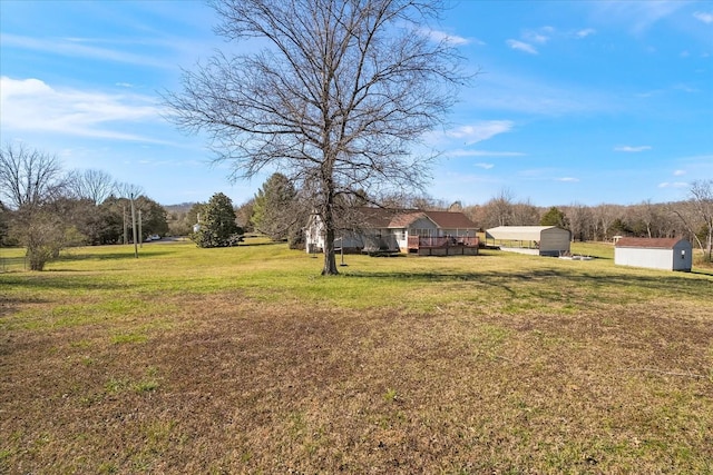 view of yard with a carport, a shed, a wooden deck, and an outdoor structure