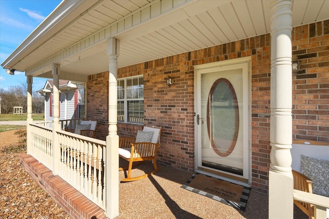 entrance to property with brick siding and a porch