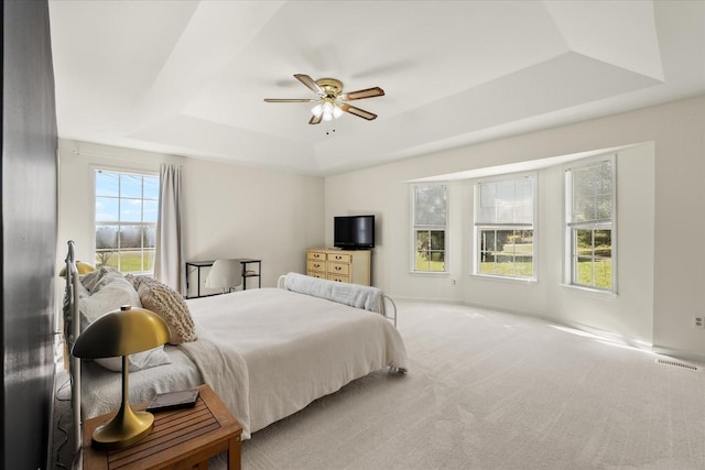 bedroom with a raised ceiling, carpet flooring, visible vents, and ceiling fan