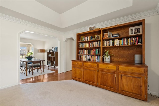 sitting room featuring arched walkways, light colored carpet, and ornamental molding