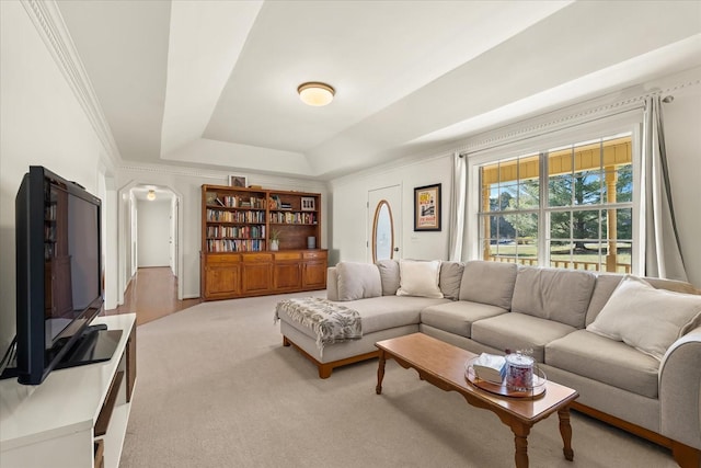 living room with arched walkways, crown molding, a raised ceiling, and carpet floors