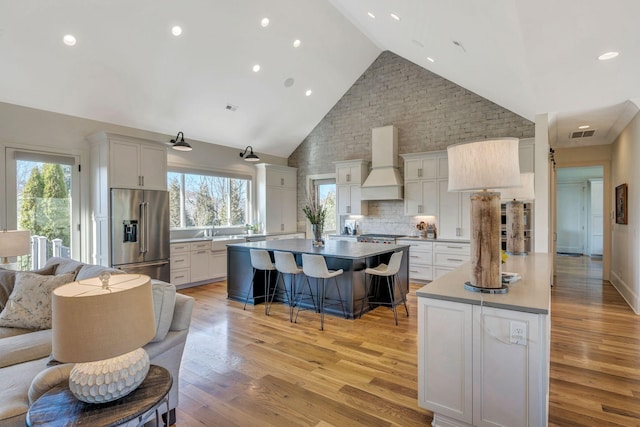 kitchen featuring a breakfast bar area, visible vents, premium range hood, a kitchen island, and stainless steel appliances