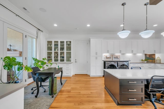 kitchen featuring white cabinetry, light countertops, light wood finished floors, and washing machine and clothes dryer