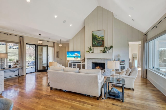 living room featuring light wood-style flooring, a healthy amount of sunlight, and a warm lit fireplace