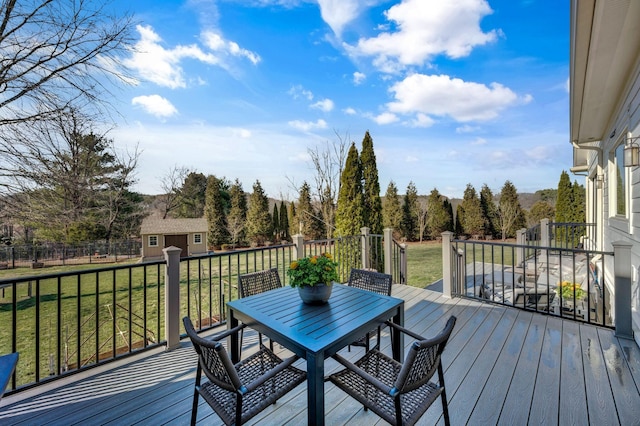 deck with a yard, an outbuilding, and outdoor dining space