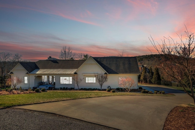 single story home featuring covered porch, curved driveway, a chimney, and a yard