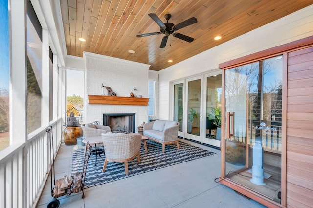 sunroom featuring wood ceiling, a ceiling fan, and an outdoor brick fireplace