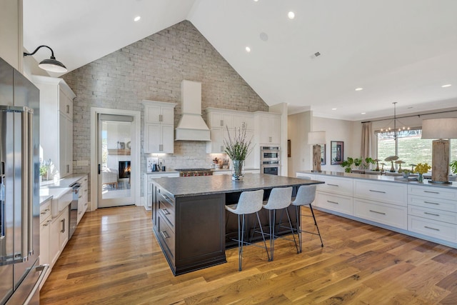 kitchen featuring premium range hood, stainless steel appliances, white cabinets, and a center island