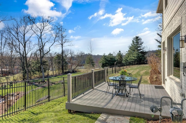 deck with outdoor dining space, a yard, and fence