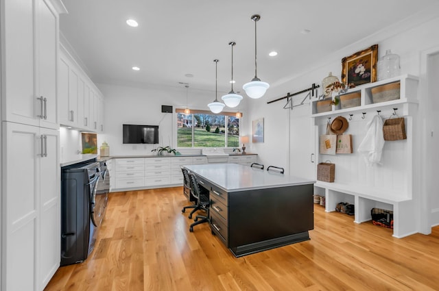 kitchen with a kitchen island, light countertops, white cabinets, pendant lighting, and light wood-type flooring