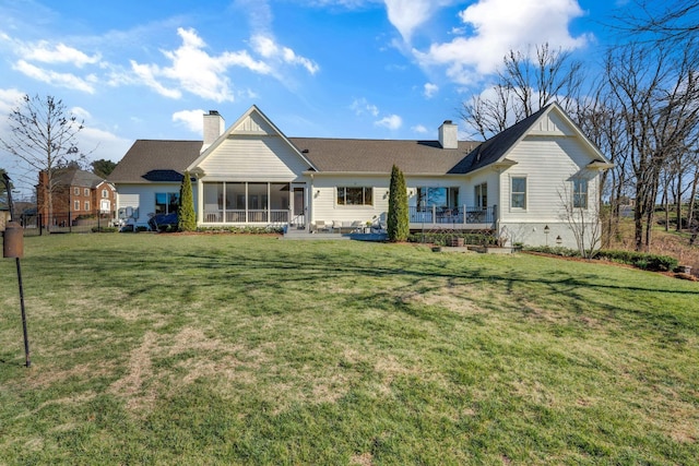 rear view of house with a lawn, roof with shingles, a chimney, and a sunroom