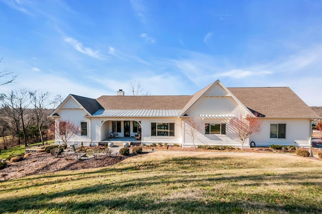 back of property with a yard, a porch, a chimney, and a shingled roof