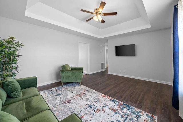 unfurnished living room with a raised ceiling, wood finished floors, a ceiling fan, and visible vents