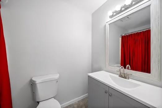 bathroom with toilet, vanity, and baseboards