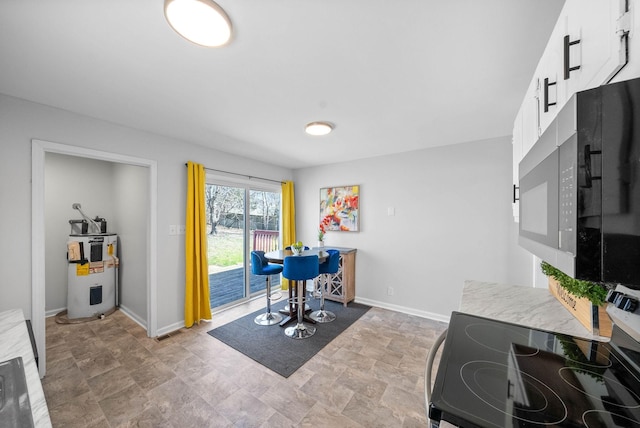 office space featuring water heater, stone finish flooring, and baseboards