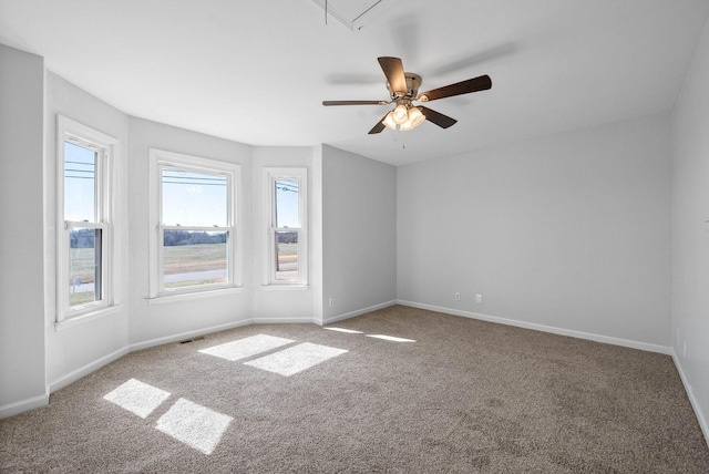 carpeted spare room featuring visible vents, baseboards, attic access, and ceiling fan