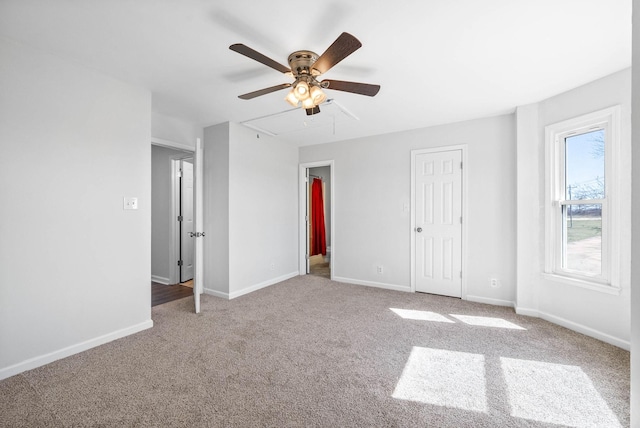 unfurnished bedroom featuring attic access, a ceiling fan, baseboards, and carpet floors