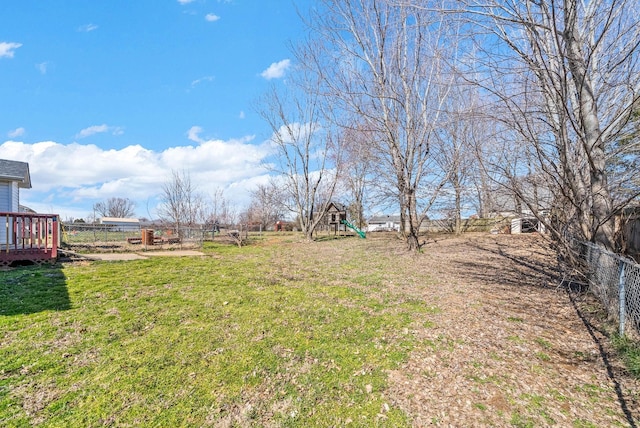 view of yard with a playground, fence, and a wooden deck