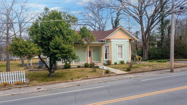 view of front of home featuring covered porch, a front lawn, and fence