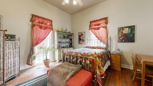 bedroom featuring multiple windows, wood finished floors, baseboards, and ceiling fan