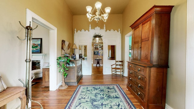 entrance foyer featuring a notable chandelier, a fireplace, baseboards, and wood finished floors