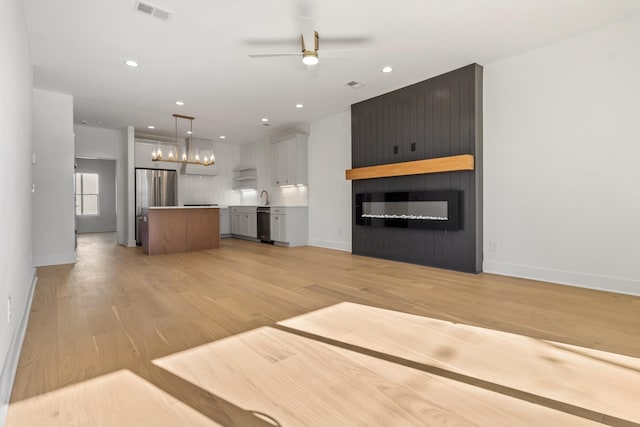 kitchen featuring visible vents, a center island, ceiling fan, open floor plan, and freestanding refrigerator