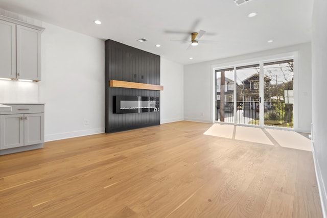 unfurnished living room with a large fireplace, baseboards, ceiling fan, light wood-type flooring, and recessed lighting