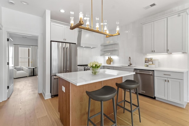 kitchen with visible vents, light wood-type flooring, custom exhaust hood, stainless steel appliances, and a sink